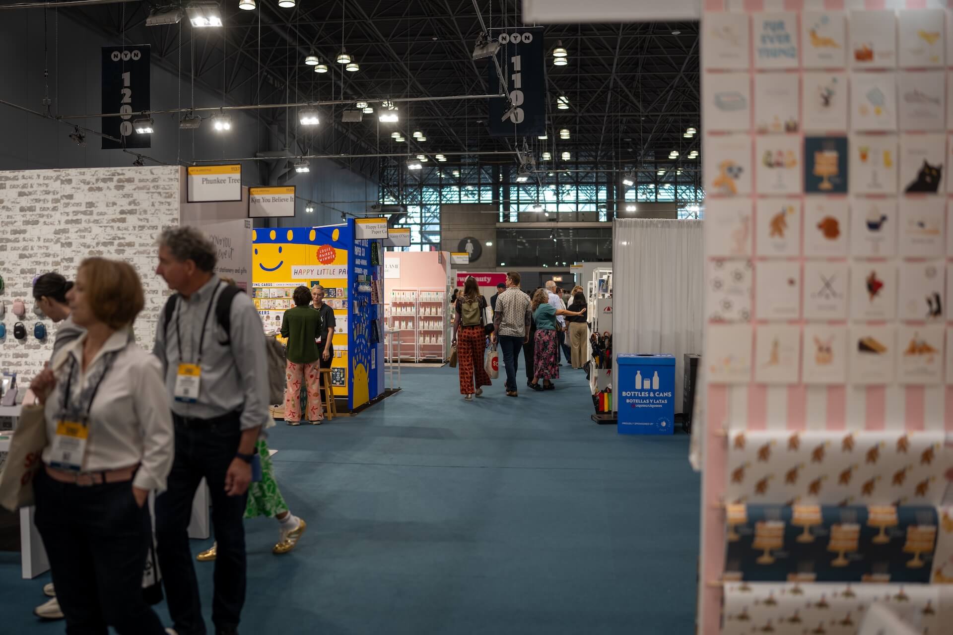 A woman shows off her wares to two buyers at a booth